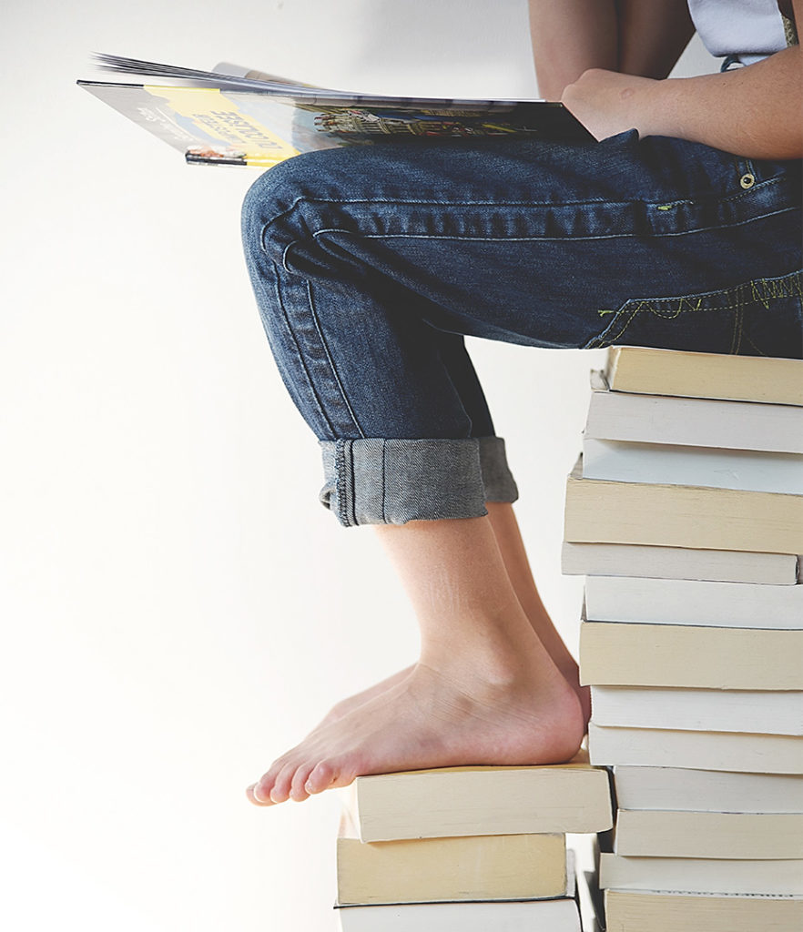 Student Sitting on Pile of Books